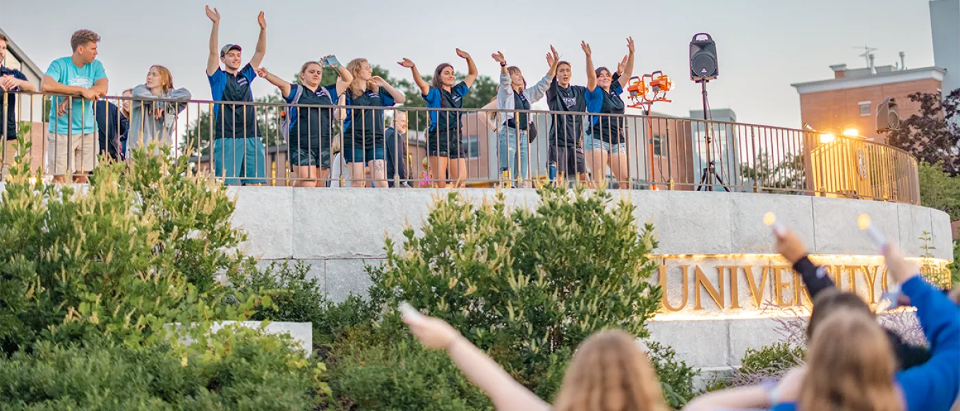 A group of students wave their hands from a terrace
