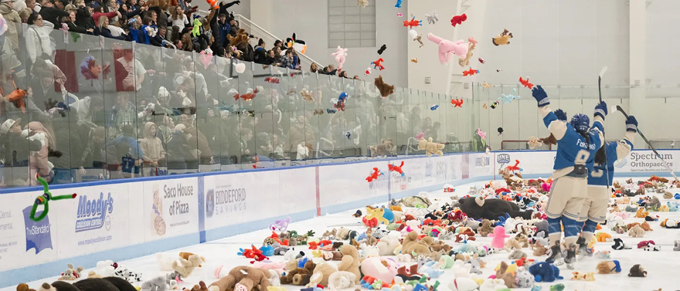 Women ice hockey players hype the crowd as the crowd throws stuffed animals into the ice rink
