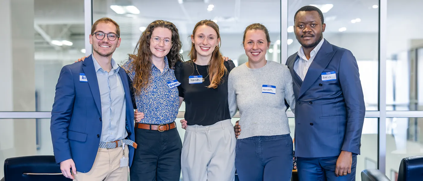 A group of five students in businesswear pose together