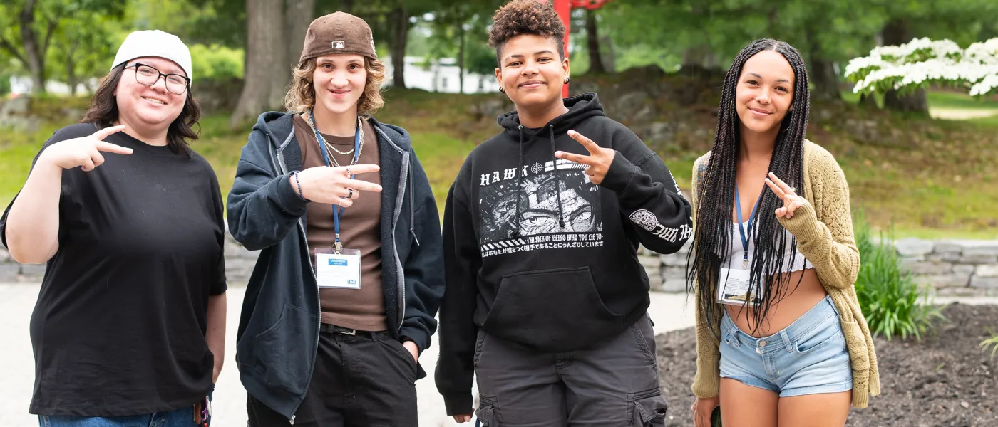 Four students pose from the camera outside on the Biddeford campus