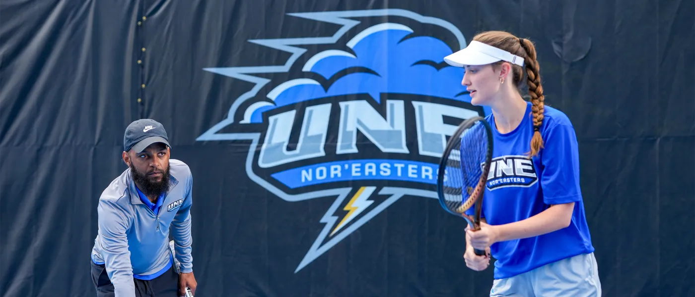 Coach Jovan Jordan-Whitter holding a tennis ball for a player to hit at the Blue Cyclone Complex.