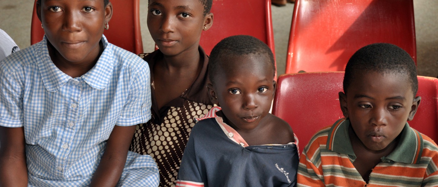 Four Ghanaian children wait to receive medical care from U N E students and faculty