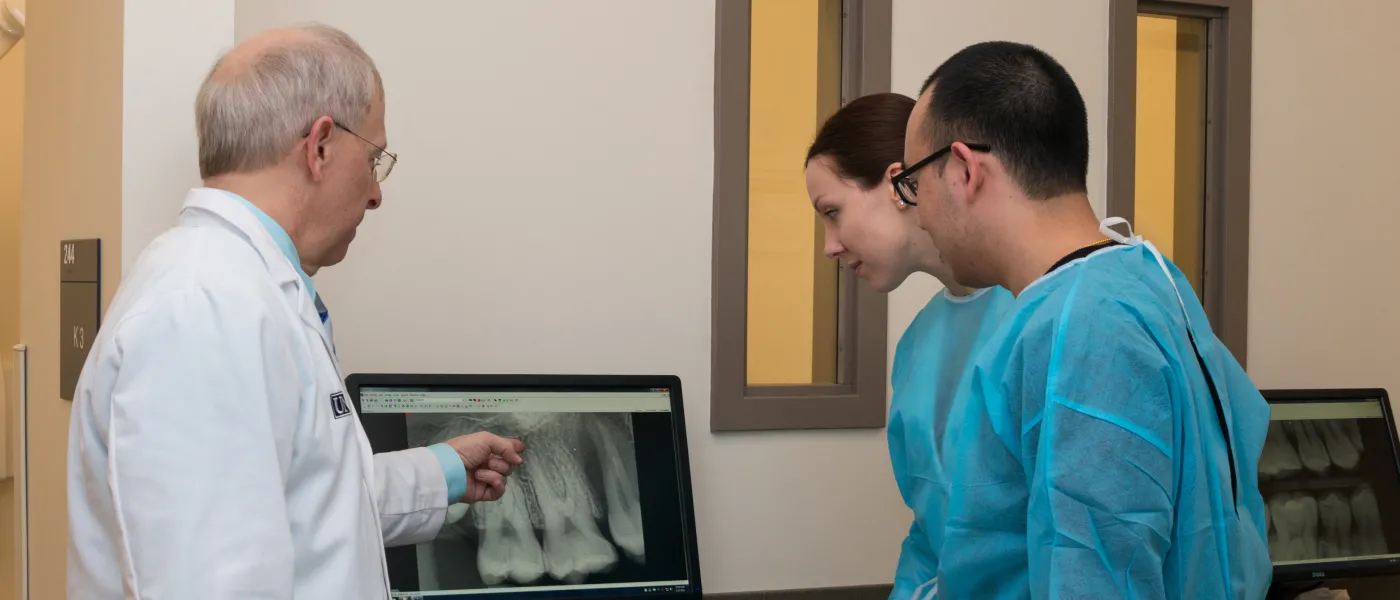 A U N E Dental Medicine faculty member and two students look at X rays