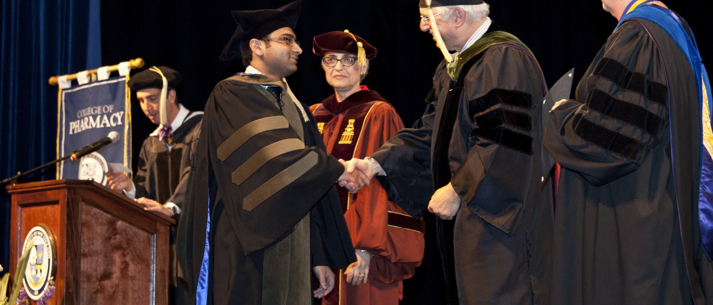 A pharmacy student accepts his diploma during commencement 