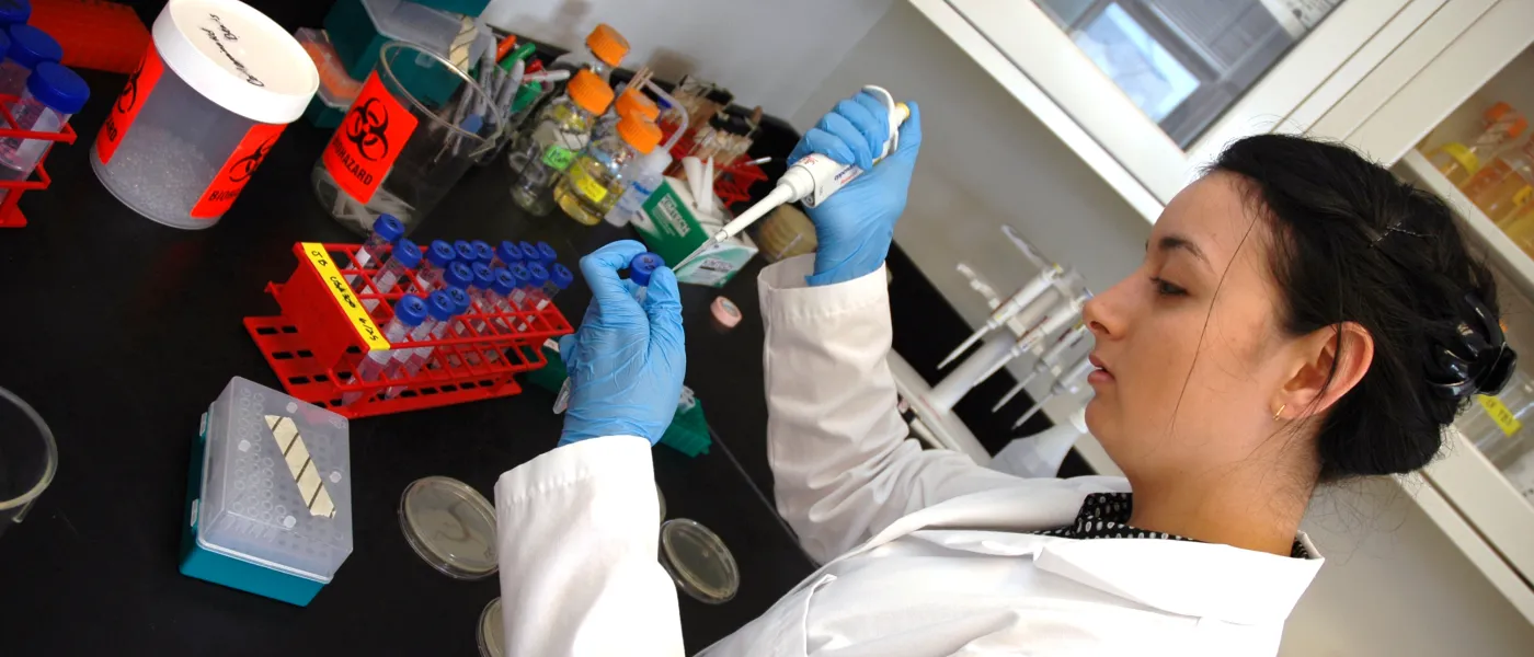 A female student extracts a sample from a test tube