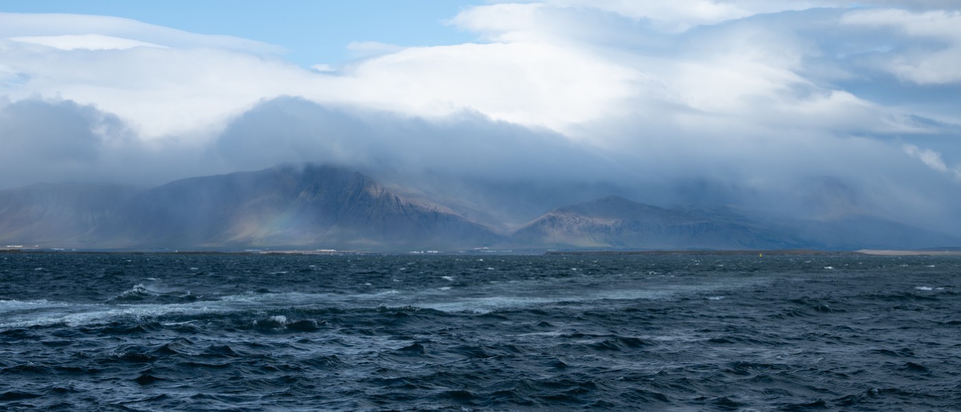 Photo of the ocean with fog and mountains in the background