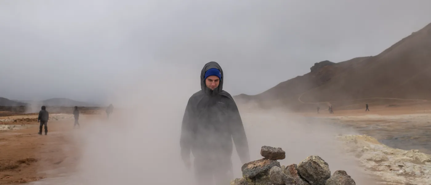 A student walks through dense fog on a rocky landscape