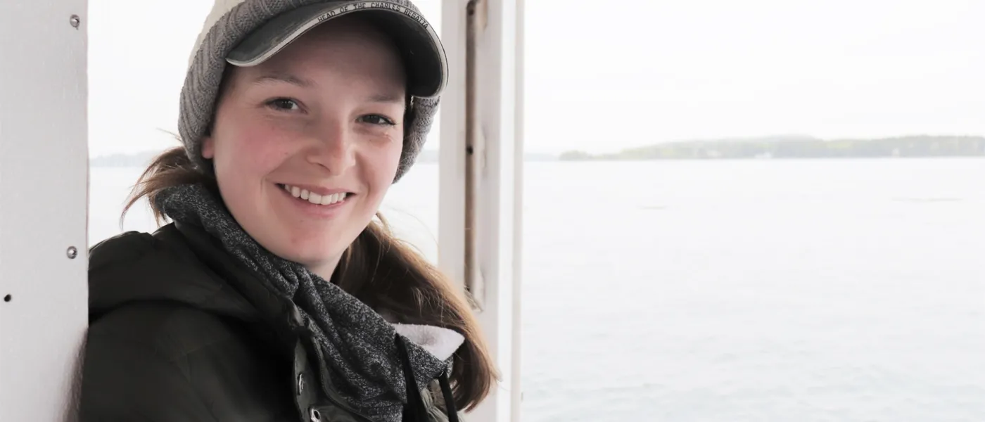 A female student poses on a boat on the water