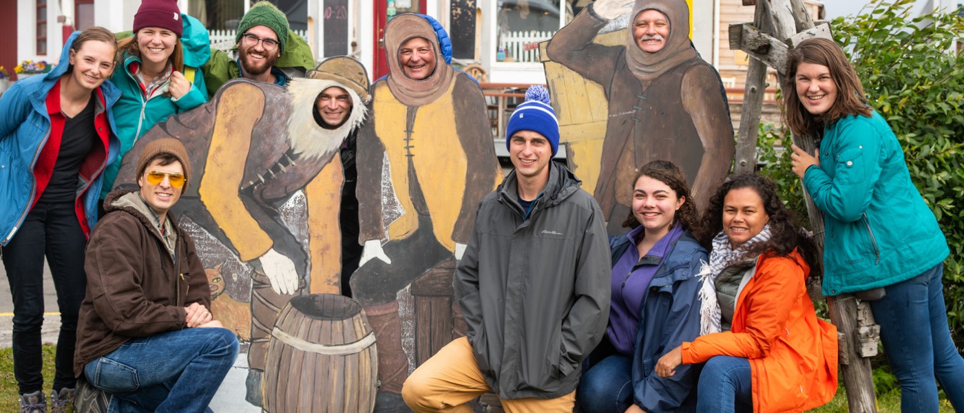 Students and professors pose with their faces in life-size cutouts while in Iceland
