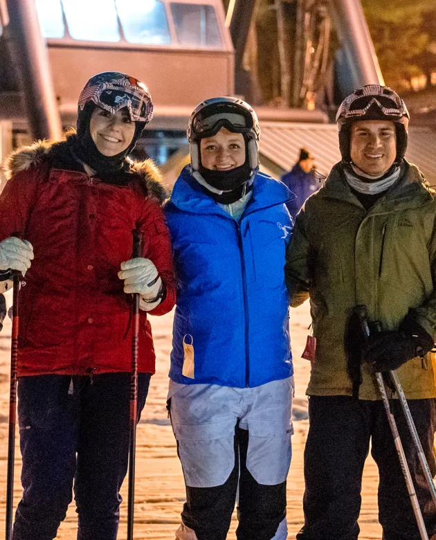 Three U N E students taking a photo on a snowy mountain during a ski trip