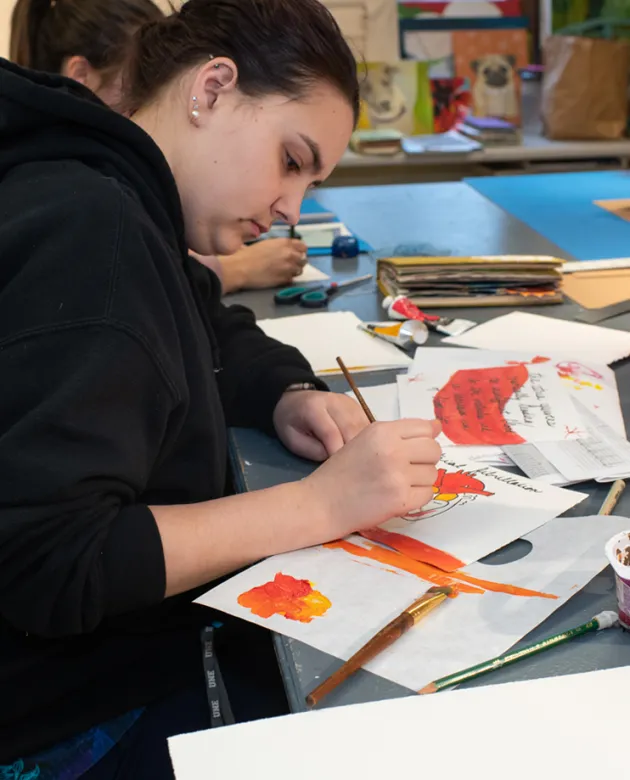 A student watercolors pages as part of a bookmaking project