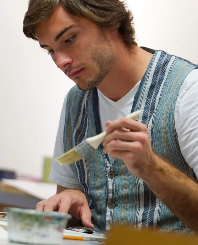 A student paints with a small paintbrush