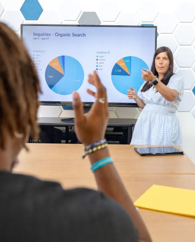 A professor points to a student raising their hand to ask a question
