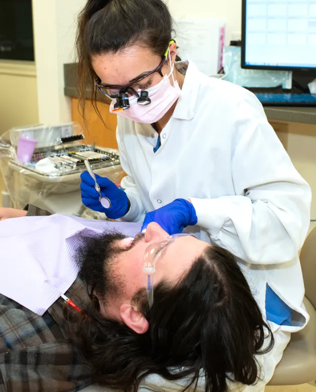 A dental hygiene student practices cleaning the teeth of a patient