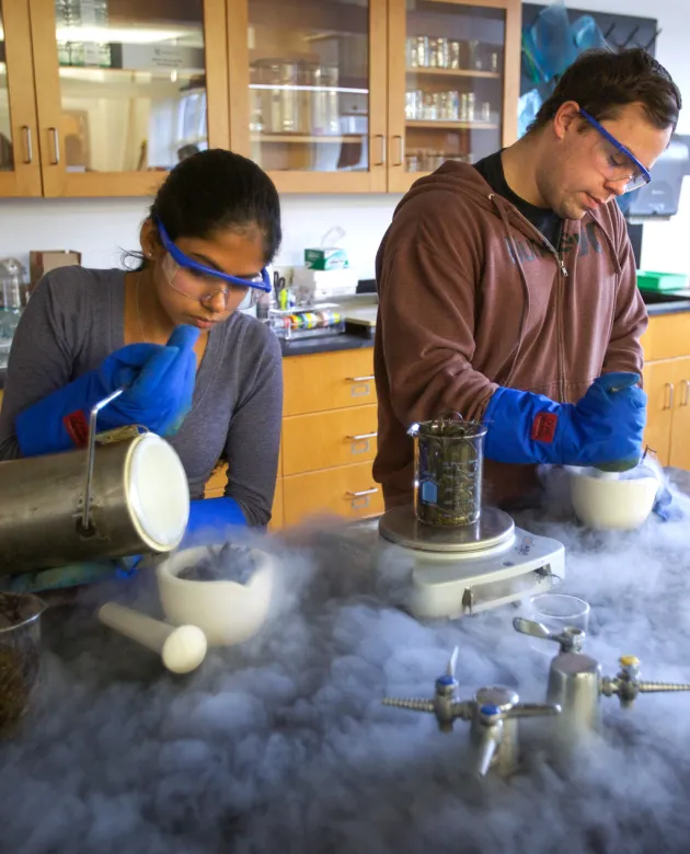 Two students working in a classroom lab create dry ice