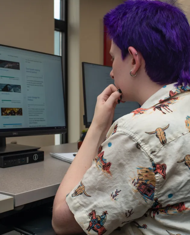 A student looks at their Brightspace homepage on a monitor in the library