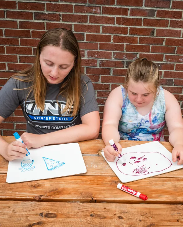 An education major draws alongside a middle school student