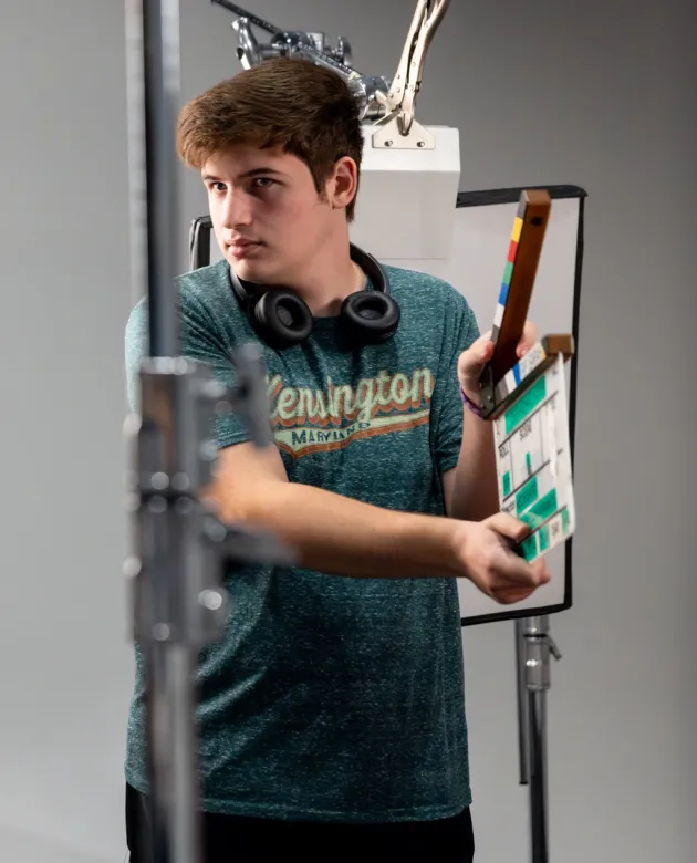 A communications student uses a clapperboard in between shots for a videotaped interview during class