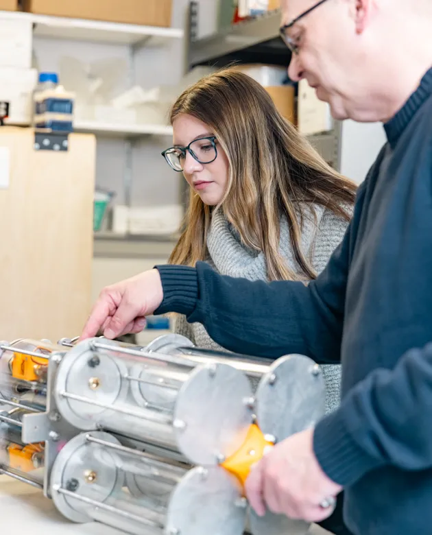 A faculty member helps a student refine a water tank for marine DNA sampling