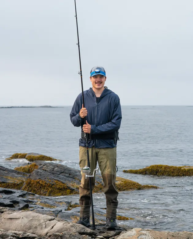 U N E student Ben Gowell holding a fishing rod for his research on stripped bass