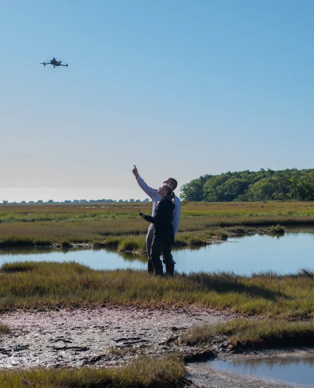 Johanna Birchem with Will Kotchtitzky flying a drone on the marsh.