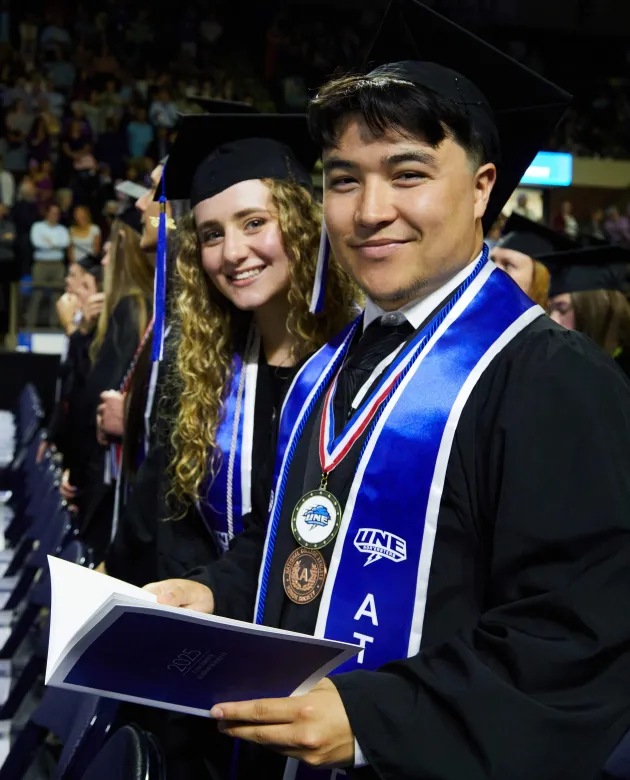 College of Arts and Sciences graduates smile in the arena
