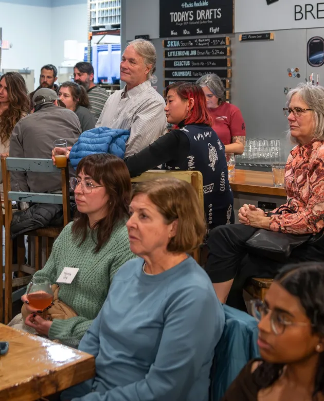 Community members sit for a presentation at a brewery