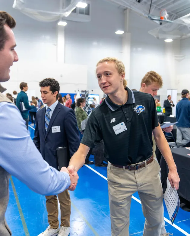 A student shakes hands with a job recruiter