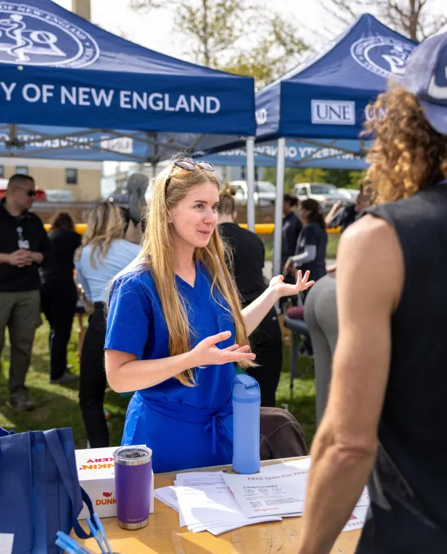 A student welcomes runners to the UNE tent