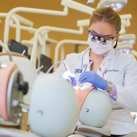 A female dental hygiene students practices on a patient simulator