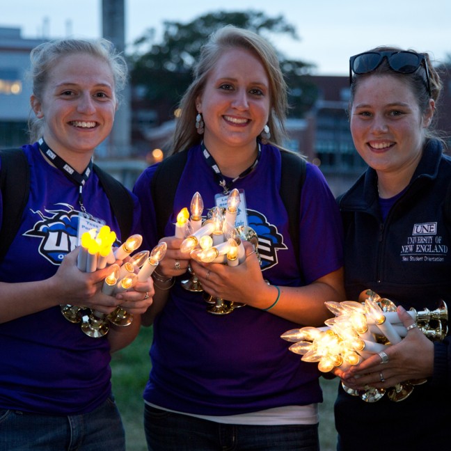 Three students hold batter powered candles at the first night event