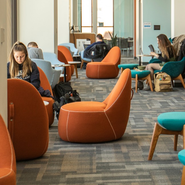 students relax and work in a common area on campus