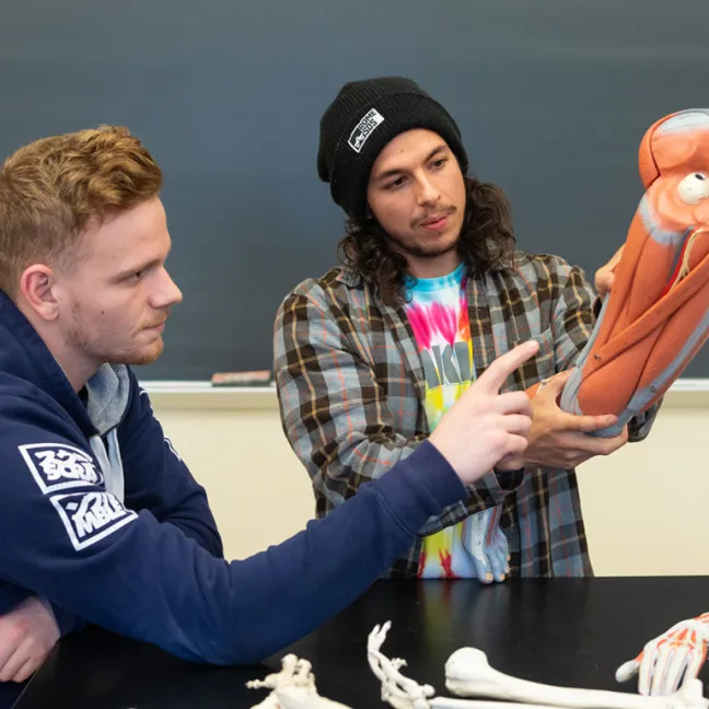 Two students investigate an object in lab