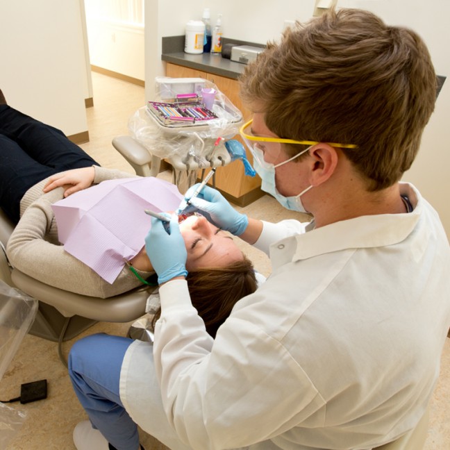 a student performs cleans a patient's teeth