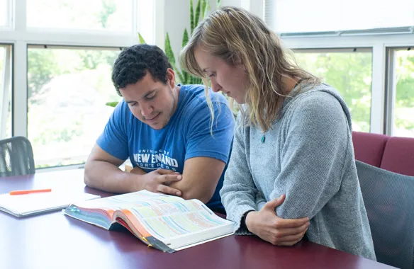 U N E students reading a text book together