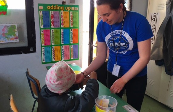 A U N E student helps a child