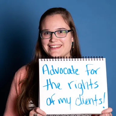A U N E social work students hold up a hand written sign that reads advocate for the rights of my clients!