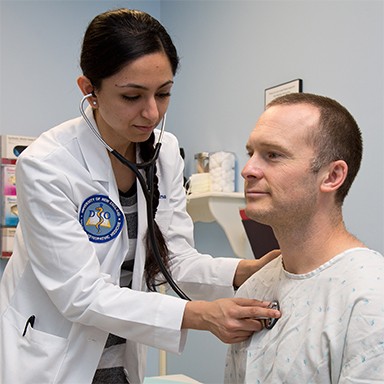 A U N E osteopathic medicine student listening to the heartbeat of a patient