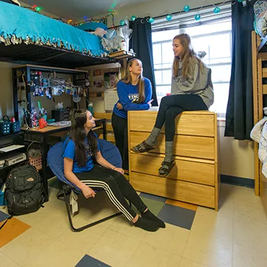 Three U N E students chatting in their dorm room