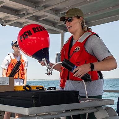 A Marine Science student holding a buoy that reads "Fish Rescue"