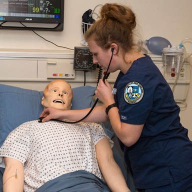 A nursing student working in the sim lab