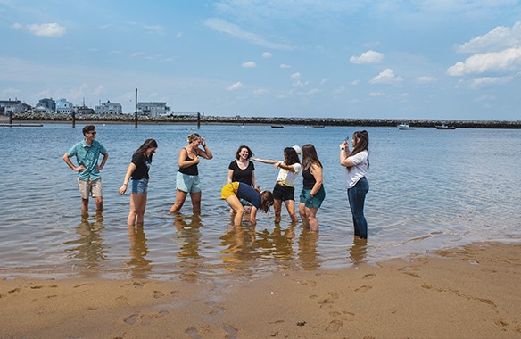 Seven U N E students standing in the ocean right off the beach
