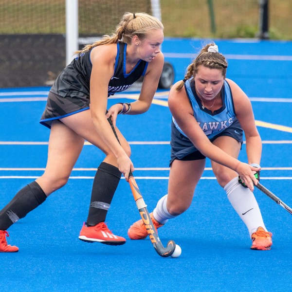 A U N E women's field hockey player during a game on the blue field