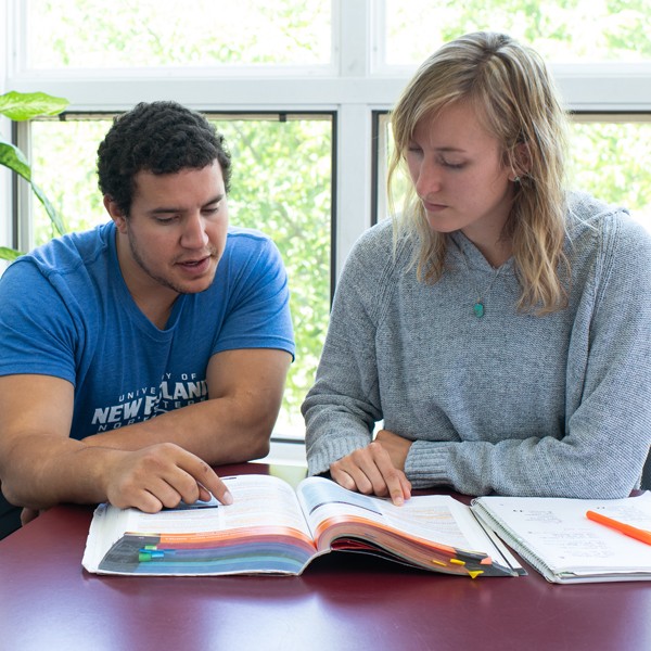Two students studying out of a shared book