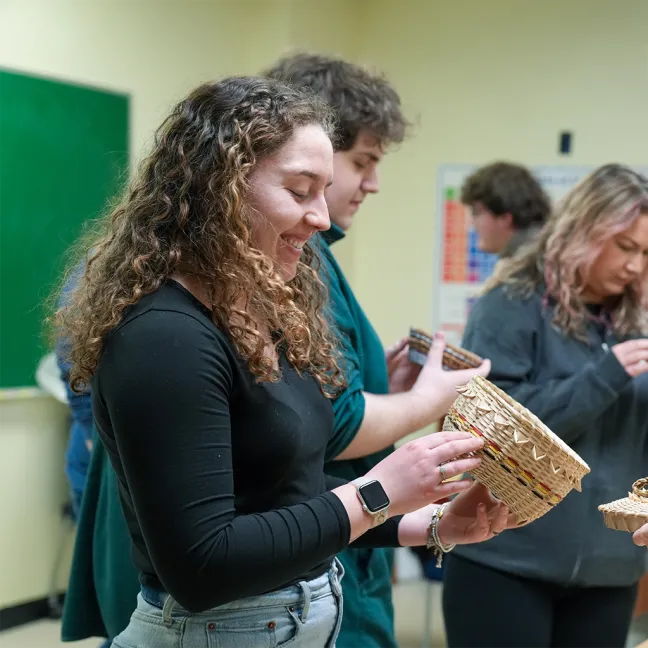 A Public History student holds a Wabanaki basket in class