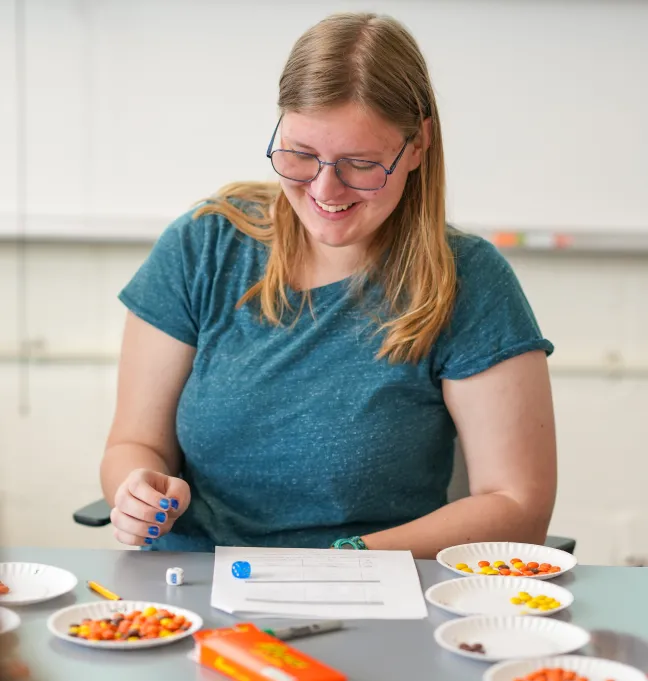 A student smiles as they roll a dice during a statistics class