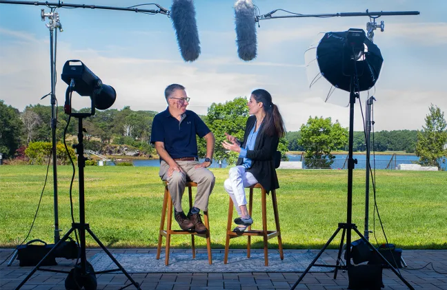 Josh Pahigian interviews Golshan Madraki seated outside while surrounded by video and audio equipment