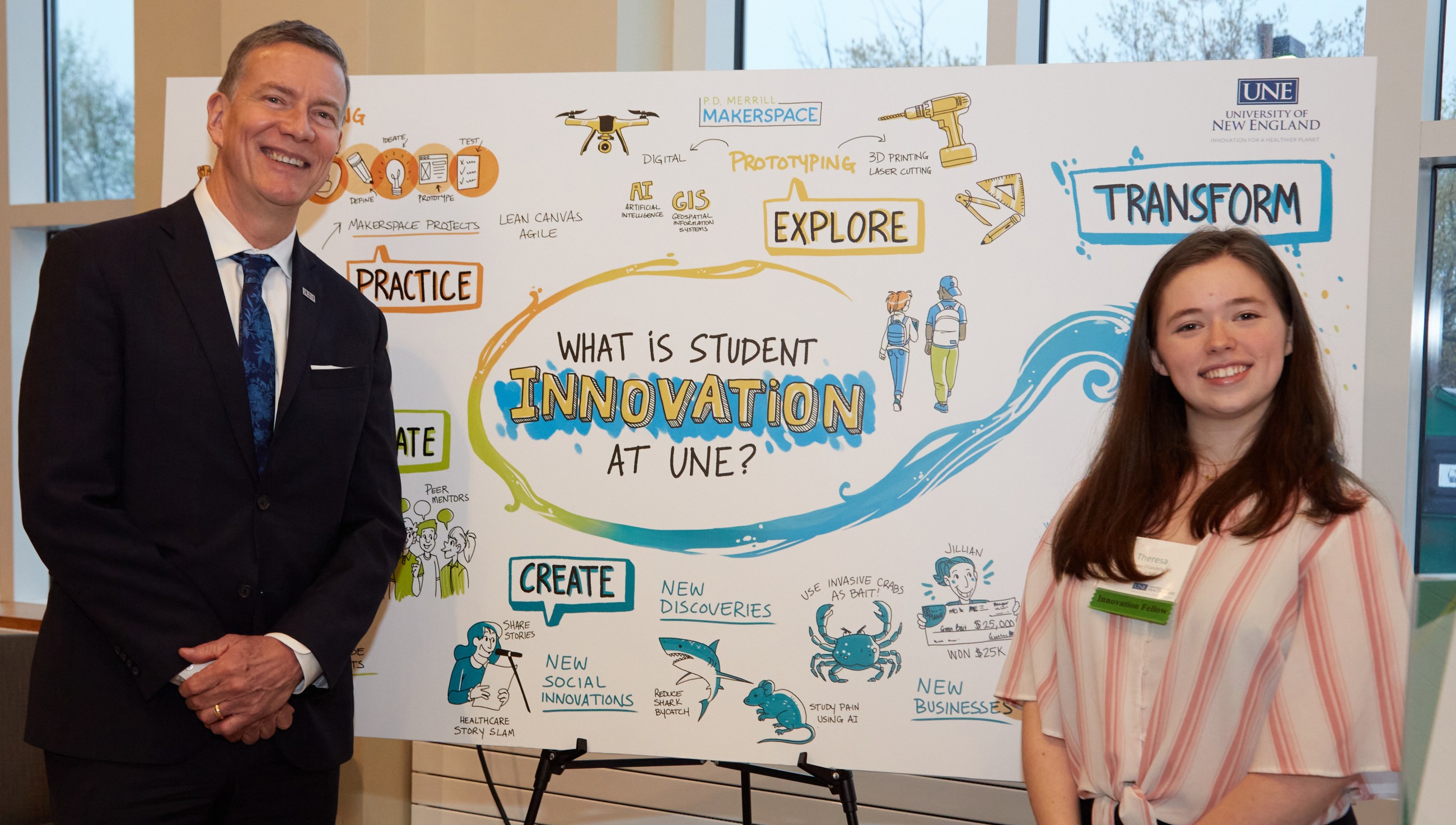 U N E president James Herbert stands with a student in front of a poster depicting innovation at U N E