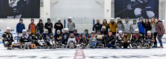 A group of PT students and volunteers/participants from Maine Adaptive post after a sled hockey demonstration at the Harold Alfond Forum