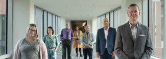 U N E faculty, a student, and President Herbert stand in a hallway